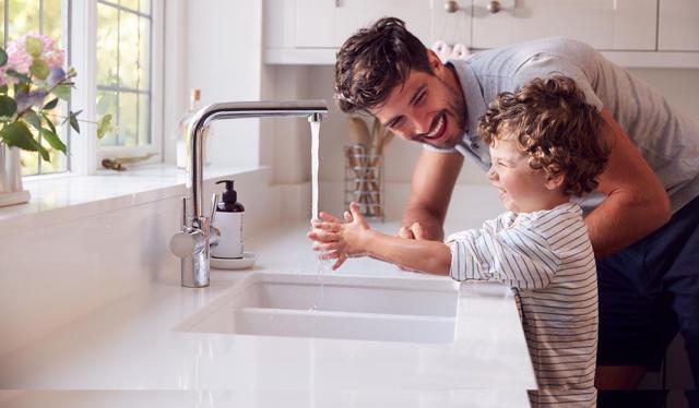 Father and son playing in water at the kitchen sink